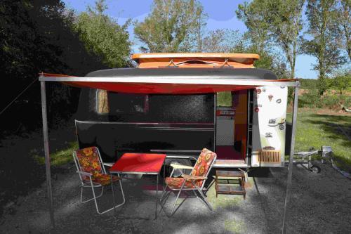 an rv with chairs and a table and a tent at La Eriba Toinette in Nort-sur-Erdre