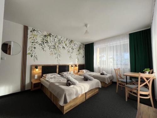 a hotel room with two beds and a table and a desk at Willa Dorota in Krynica Zdrój