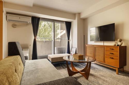 a living room with a couch and a tv and a table at Cozy Stay Sapporo Central 301 in Toyohira