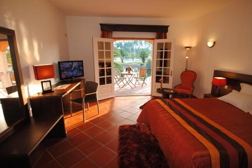a hotel room with a bed and a desk and a balcony at Herdade Lago Real in Praia de Mira