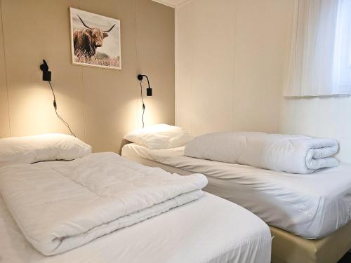 2 Betten in einem Zimmer mit weißer Bettwäsche in der Unterkunft Chalet Noelle SE14 in Serooskerke