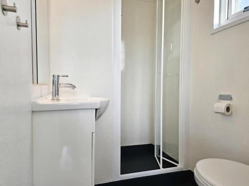 ein weißes Bad mit einem Waschbecken und einer Dusche in der Unterkunft Chalet Noelle SE14 in Serooskerke