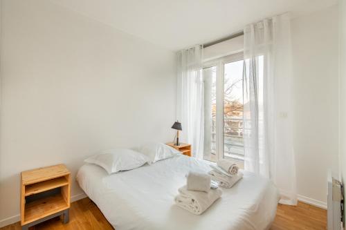 a white bedroom with a bed and a window at Panhard - Cosy place proche Gare de Lyon in Paris