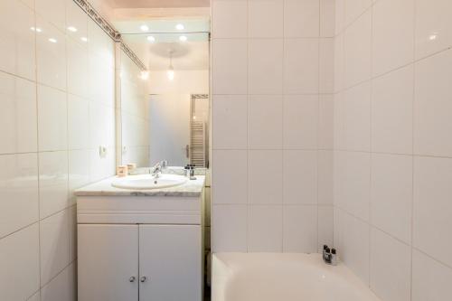 La salle de bains blanche est pourvue d'un lavabo et d'un miroir. dans l'établissement Panhard - Cosy place proche Gare de Lyon, à Paris