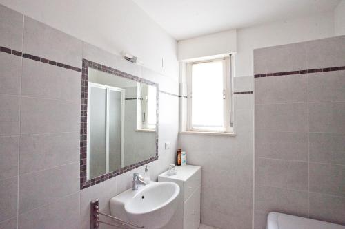 ein weißes Badezimmer mit einem Waschbecken und einem Spiegel in der Unterkunft La Casa Di Lavinia in Nago-Torbole