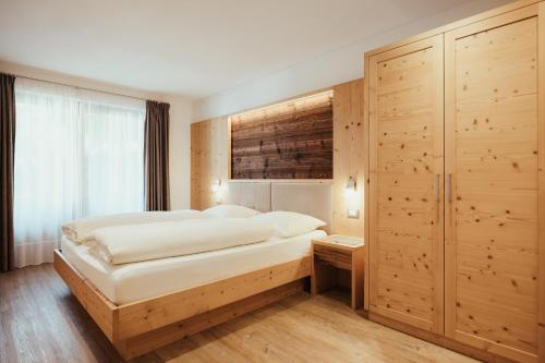 um quarto com uma cama grande e uma parede de madeira em Chalet La Flüta Arnica em La Valle