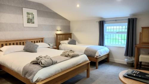 a bedroom with two beds and a table and a window at The Saxon Inn in Bishop Auckland