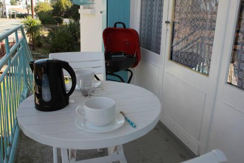 - une table blanche avec 2 tasses et une bouilloire sur une terrasse couverte dans l'établissement Ronce-les-Bains - APPARTEMENT 1er ETAGE gauche - 90m de la PLAGE, à Ronce-les-Bains