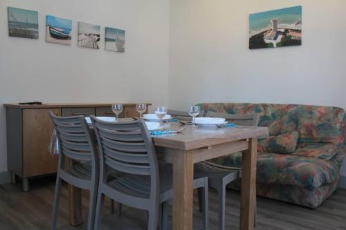 - une table à manger avec des chaises et un canapé dans l'établissement Ronce-les-Bains - APPARTEMENT 1er ETAGE gauche - 90m de la PLAGE, à Ronce-les-Bains
