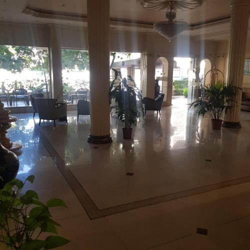 a lobby with tables and chairs and a hallway with columns at فندق زهرة الخليج in Dammam