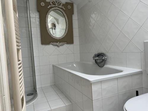 uma casa de banho branca com uma banheira e um espelho. em Monumental house, apartment in Center Haarlem em Haarlem
