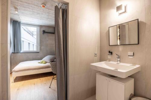 a bathroom with a sink and a bed in a room at Lumen by coliving in Renens