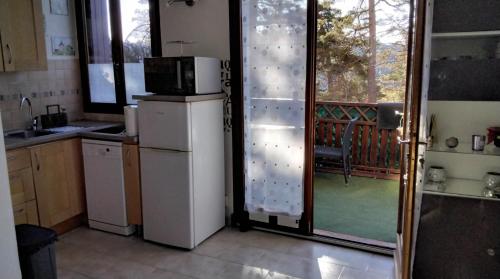 une cuisine avec un réfrigérateur et une porte coulissante en verre dans l'établissement LA PETITE TOURELLE, à Thorenc