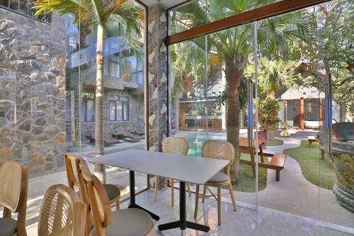a dining room with a table and chairs and palm trees at Tam Coc Serenity Hotel & Bungalow in Ninh Binh