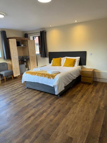 a bedroom with a large bed and wooden floors at Lillypool Farm in Shipham