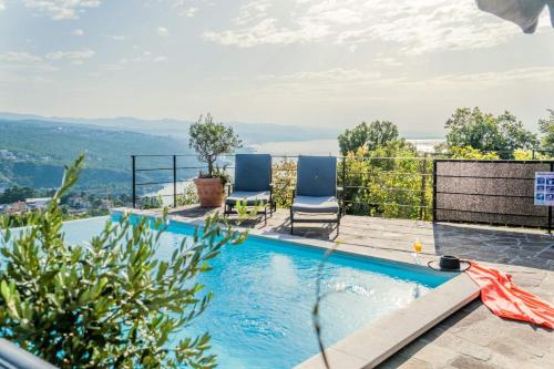 a swimming pool with two chairs and a view at Villa Izzi Opatija in Opatija