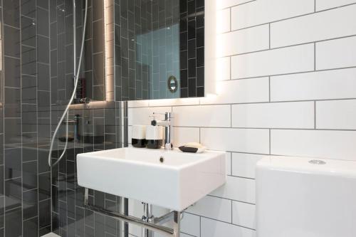 bagno bianco con lavandino e doccia di Utopian Modern Apartments a Londra