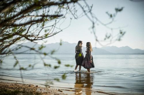 two women standing in the water on the beach at Ferienhaus Seerose in Übersee