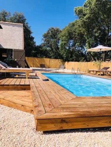 une piscine avec une terrasse en bois et une piscine dans l'établissement La Petite Siffrette, à Saint-Siffret