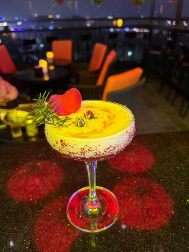 a yellow drink in a glass on a table at Bella Premier Hotel & Rooftop Skybar in Hanoi
