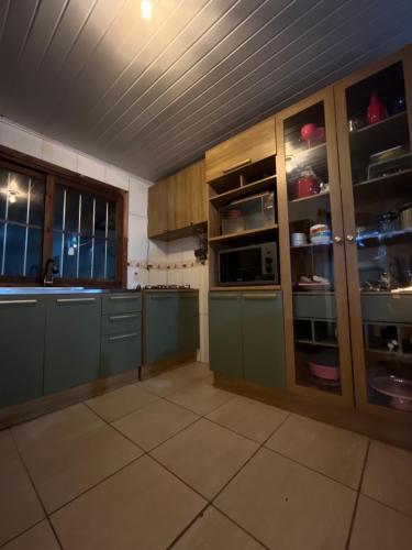 eine große Küche mit grünen Schränken und Fenstern in der Unterkunft Legítima casa de praia in Capão da Canoa