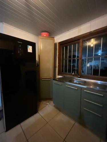 a kitchen with a sink and a window in it at Legítima casa de praia in Capão da Canoa