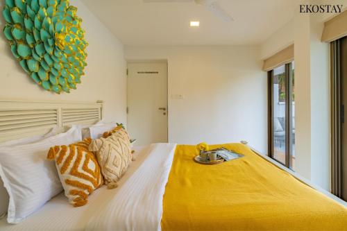 a bedroom with a bed with a yellow blanket on it at EKOSTAY Luxe - Casa Marina in Candolim