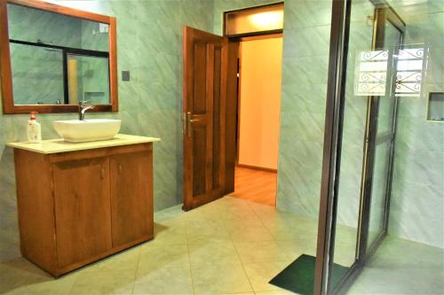 uma casa de banho com um lavatório, um espelho e um chuveiro em Ezeife Guesthouse em Kampala