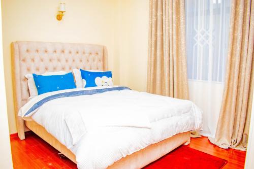 ein Schlafzimmer mit einem weißen Bett mit blauen Kissen und einem Fenster in der Unterkunft Wonderstay in Nairobi
