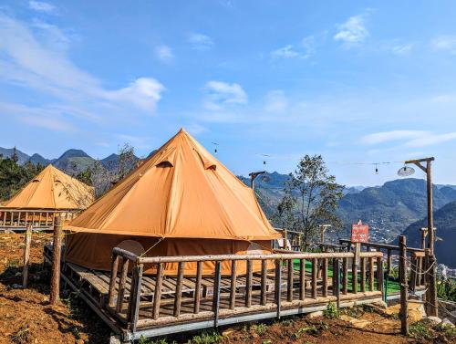 een paar tenten naast een houten hek bij De Chia Campsite in Mèo Vạc
