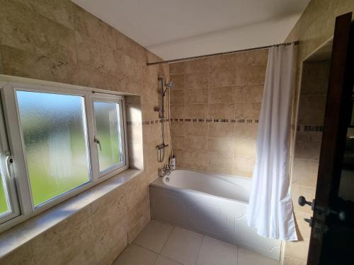 a bathroom with a bath tub and a window at Maryland Cottage Nr Gatwick in Godstone