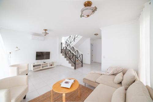 Sala de estar blanca con sofá y mesa en Villa Fariones, en Tías