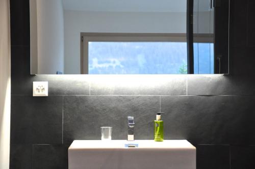 ein Badezimmer mit einem weißen Waschbecken und einem Spiegel in der Unterkunft Panoramic Ecodesign Apartment Obersaxen - Val Lumnezia I Vella - Vignogn I near Laax Flims I 5 Swiss stars rating in Vella