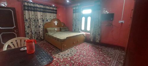 una camera con letto, tavolo e finestra di KRISHNA HOMESTAY a Bhadarwāh