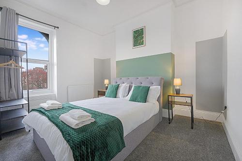 a bedroom with a large bed with green and white sheets at Cozy Home in Avenue Terrace, Sleeps 8 in Sunderland