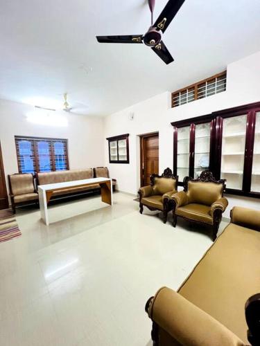 a living room with couches and a ceiling fan at Home in Guruvayur-3 Bedroom(1AC)+Living+Kitch in Guruvāyūr