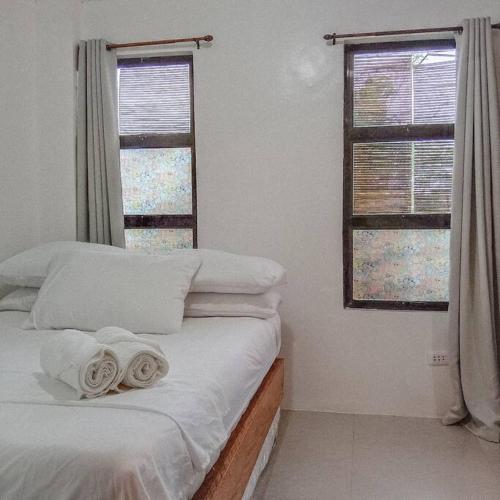 1 dormitorio con 1 cama con sábanas blancas y 2 ventanas en 1-BR flat with kitchen private bath hot and cold shower, en General Luna