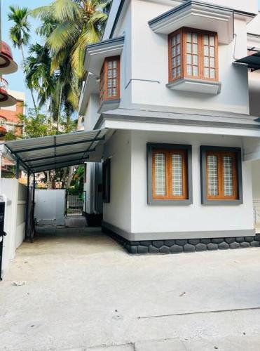 a white house with an awning in front of it at Home in Guruvayur-3 Bedroom(1AC)+Living+Kitch in Guruvāyūr