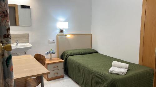 Habitación pequeña con cama y lavamanos en Hostal Alhambra Tarragona, en Tarragona