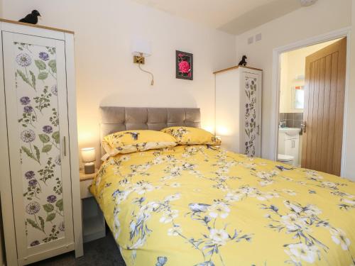 a bedroom with a yellow bed with flowers on it at The Annexe in Fakenham