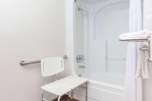 a white bathroom with a shower and a white bench at Days Inn by Wyndham San Francisco S/Oyster Point Airport in South San Francisco