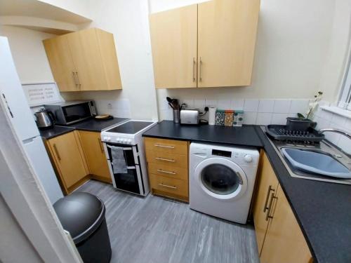 a small kitchen with a washing machine and a sink at Comfortable 2beds house 4 contractors & staycation in Leeds