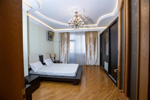 1 dormitorio con cama y lámpara de araña en WAQAS RESIDENCE INTERNATIONAL, en Baku