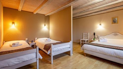 a bedroom with two beds and a wooden ceiling at Hôtel - Restaurant Le Couchetat in La Bresse