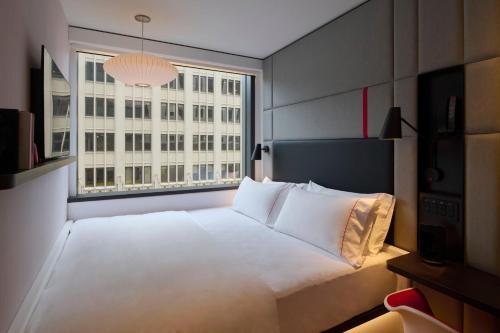 a bedroom with a large white bed and a window at citizenM Austin Downtown in Austin