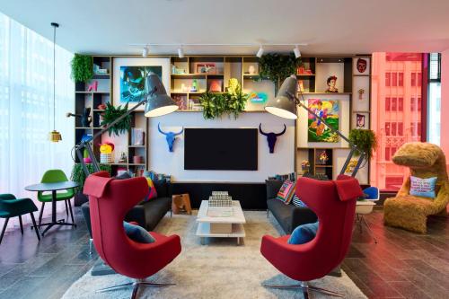 a living room with red chairs and a flat screen tv at citizenM Austin Downtown in Austin
