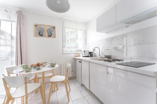 - une cuisine blanche avec une petite table et des chaises dans l'établissement Le Rex - Bel appt avec sauna, à Nantes