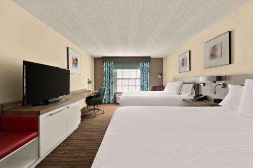 a hotel room with two beds and a flat screen tv at Hilton Garden Inn Williamsburg in Williamsburg
