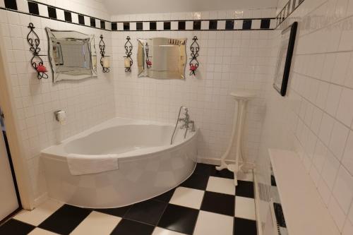 a white tub in a bathroom with a checkered floor at The Mary Arden Inn in Stratford-upon-Avon