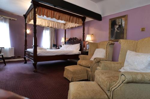 1 dormitorio con cama con dosel y sofá en The Mary Arden Inn en Stratford-upon-Avon